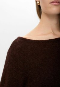 Pulover din lână maro cu un decolteu larg și o textură moale, având o croială confortabilă și relaxată, cu detalii minime.