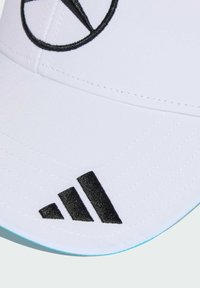 White cap with black embroidered logo and three black stripes. Features a flat brim and stitched texture, with a light blue underside.