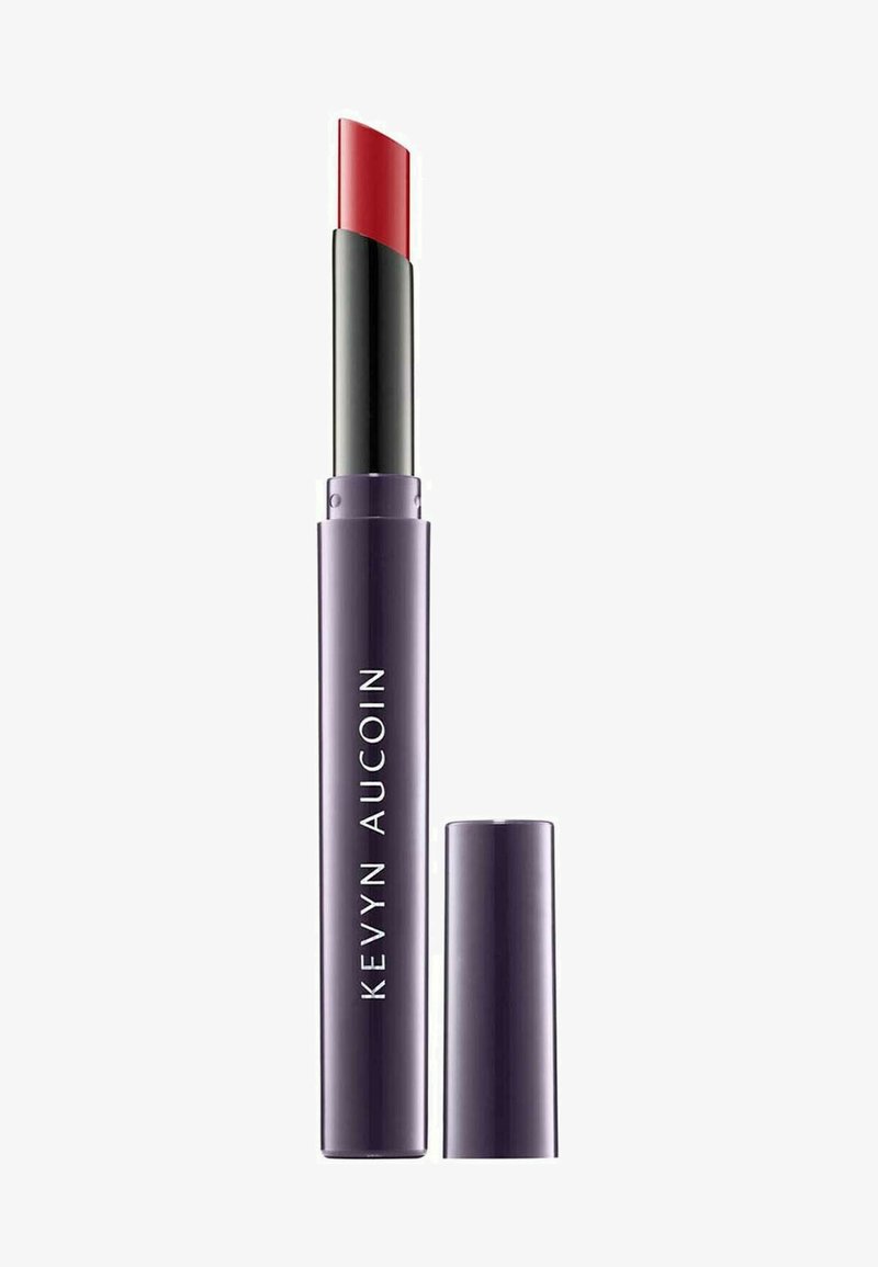Rossetto rosso in un tubo viola con punta affusolata. Presenta una parte nera alla base. Cappuccio rimosso, mostrando forma e colore del prodotto.