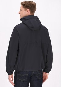 Marine windbreakerjack met een capuchon, elastische manchetten en een losse pasvorm. Kenmerkt zich door een gladde, lichte stof met minimale naden.