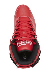 Basket en cuir perforé rouge, montante, avec doublure noire, lacets rouges et détails de logo blanc sur la languette et le côté.