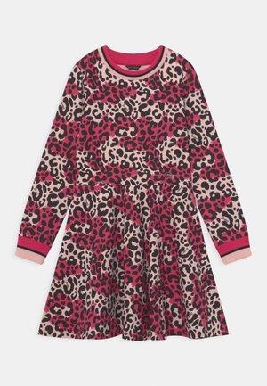 Długa sukienka z długim rękawem w miękkim materiale, z różowo-czarnym i beżowym wzorem w panterkę. Dekolt oraz mankiety rękawów są prążkowane w kolorze różowym z czarnymi akcentami.