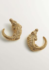 Pendientes en forma de cocodrilo en tono dorado que presentan escamas detalladas, un diseño de cola enroscada y un acabado texturizado para mayor dimensión.