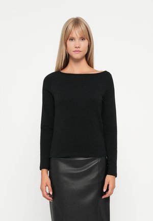 Haut noir à manches longues avec un col bateau, fabriqué dans un tissu lisse. Il a une silhouette ajustée et est associé à une jupe noire.