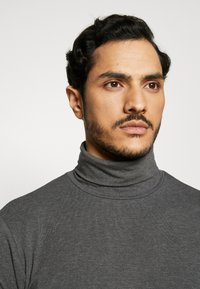 Grau Rollkragenpullover aus einem glatten, strukturierten Stoff. Verfügt über einen hohen Kragen und ein figurbetontes Design.