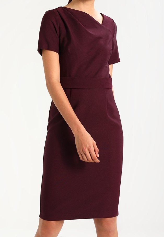 Gravidklänning i djup burgunder, med korta ärmar, en figurnära silhuett och en midjeaccent. Smoj g fabric med en lätt glans.