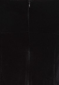 Robe en velours noir avec une texture lisse, dotée d'une couture centrale et d'une fermeture éclair discrète à l'arrière.