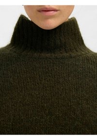 Temno zelena pletena pulover s turtleneck ovratnikom, ki ima rebrast ovratnik in teksturirano tkanino, prikaz podrobnosti, ki izpostavlja mehkobo in debelino.