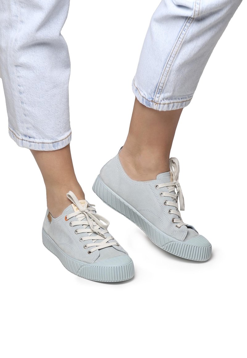 Heledad sinine suedesneakerid, ümmarguse varbaga, nööbiga disain ja tekstuuriga kummitald. Aktsendid hõlmavad kuldseid silte ja siledat viimistlust.