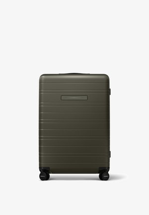Olive green hardshell suitcase with horizontal ridges, a top handle, a black luggage tag slot, and four black wheels for mobility.