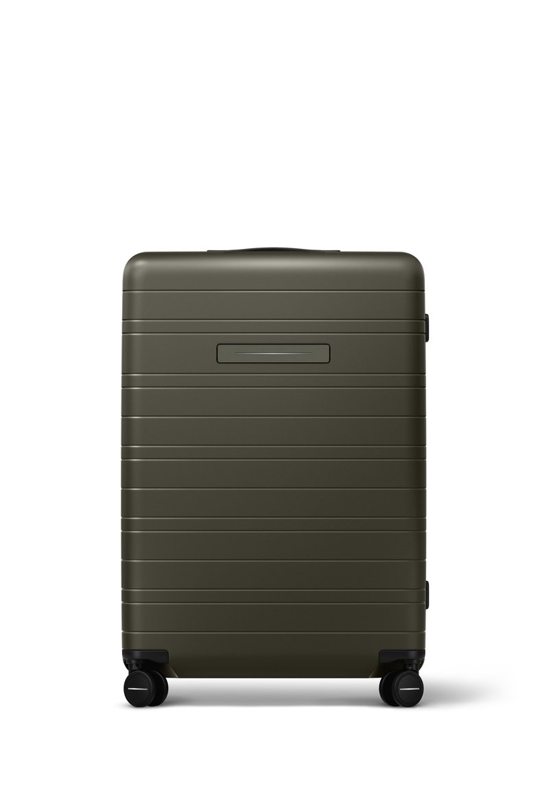 Valise rigide vert olive avec des stries horizontales, une poignée supérieure, un emplacement pour une étiquette de bagages noire et quatre roues noires pour la mobilité.