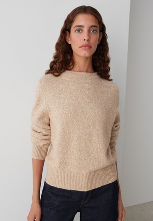 Pull en maille beige avec un motif texturé, des poignets et un ourlet à côtes. Matière douce avec de subtils flocons blancs. Conçu avec un col rond.