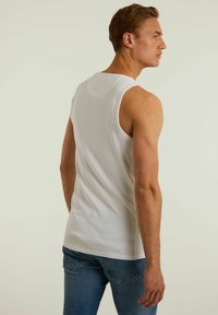 Top alb fără mâneci, realizat din bumbac, cu decolteu rotund și un design ajustat, asortat cu blugi din denim albastri.