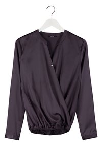 Blouse à manches longues violet foncé avec devant croisé et ourlet élastique, suspendue sur un cintre blanc sur fond blanc.