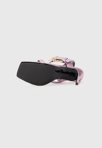 Purple glitter heeled sandal with a black sole, featuring gold hardware and a strap design. Smooth texture with a solid heel.