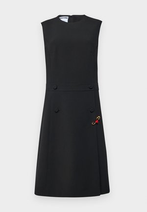 Crna haljina bez rukava sa uskim korzetom, raširenim suknjama, prednjim dugmadi i zlatnim brošem s crvenim akcentima sa strane.