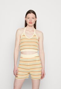 Conjunto de top e calções de malha com um padrão ondulado em amarelo pastilha, laranja e verde. O top tem um design de halter e é cortado.