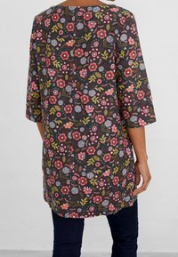 Blommig tunika med trekvartslånga ärmar. Mörk bakgrund med färgglada blommor, bladmönster och rak nederkant. Texturerad tyg.