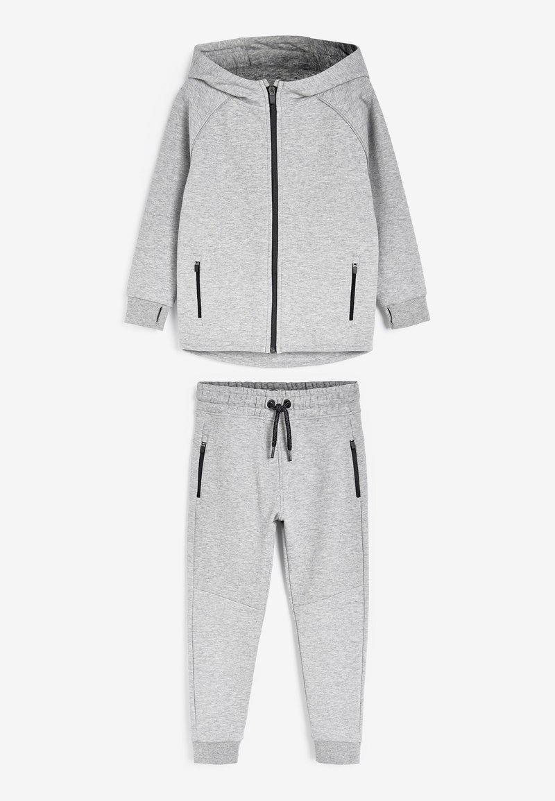 Ensemble de sweat à capuche gris et pantalon de jogging assorti, fabriqué en matériau doux, avec des poches zippées et une taille à cordon de serrage. Texture lisse et design décontracté.