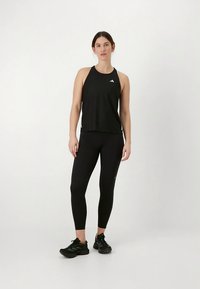 Camiseta deportiva sin mangas negra y leggings hechos de tela suave. La camiseta presenta un diseño de espalda de corredor, mientras que los leggings tienen una silueta ajustada.