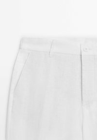 Weiße Leinenhosen mit glatter Textur, Knopfverschluss und seitlichen Taschen mit einem dezenten gewebten Muster.