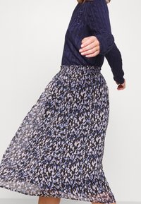 Floral-patterned skirt with shades of blue and lavender on a black background. Lightweight fabric with a flowing design and elastic waistband.