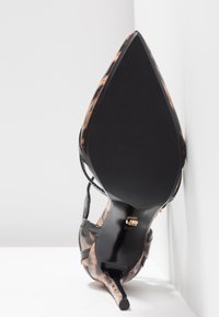 Scarpa nera con tacco alto, punta affusolata e accenti in stampa leopardata. Presenta sottili cinturini e una suola nera liscia e affusolata. Taglia 37.