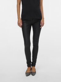 Jean skinny noir à la coupe élégante, confectionné dans un tissu lisse. Associé à des ballerines à bout pointu, avec une tige en mesh et des décorations de perles.