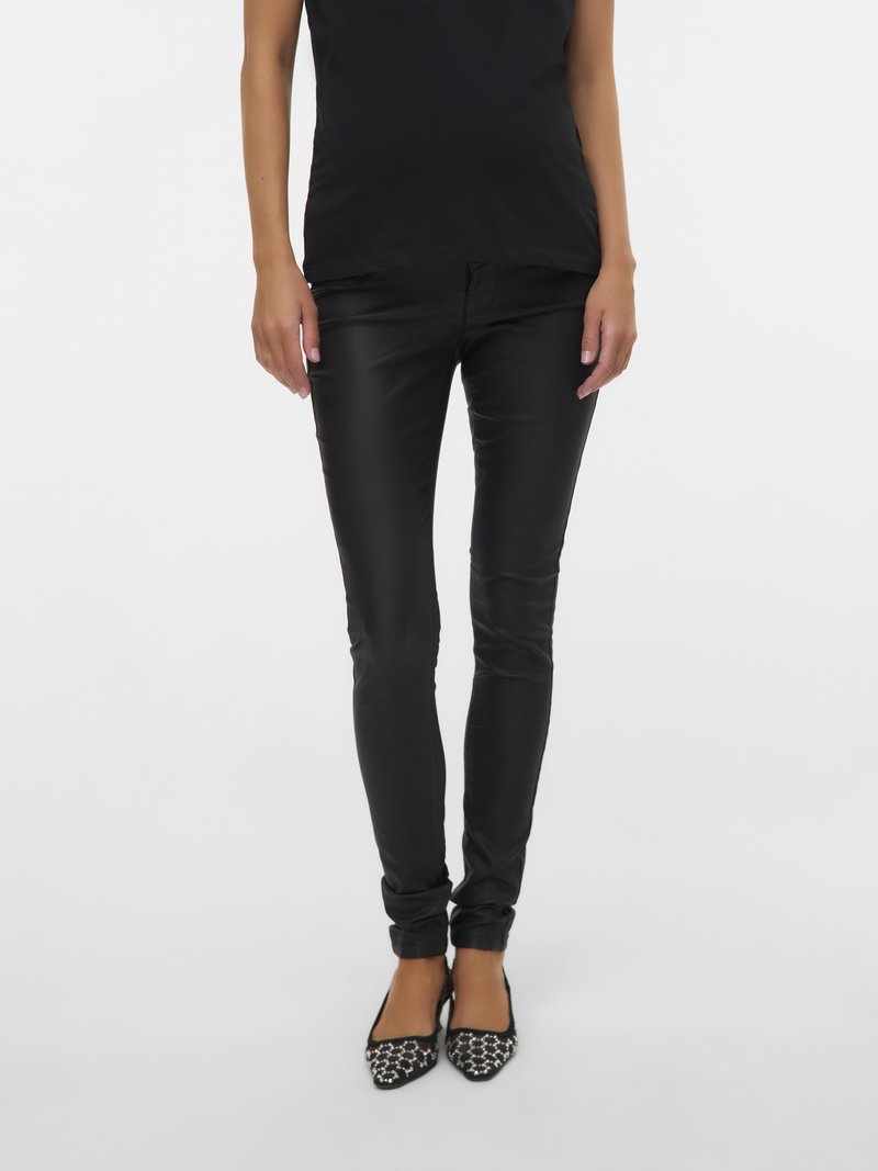 Jean skinny noir à la coupe élégante, confectionné dans un tissu lisse. Associé à des ballerines à bout pointu, avec une tige en mesh et des décorations de perles.