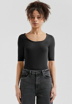Bodysuit noir à manches courtes avec col en scoop, texture lisse et design ajusté, associé à un jean en denim gris taille haute.