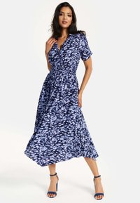 Blue printed dress with short sleeves, smocked waist, and a flowing skirt. Fabric features a textured pattern blending navy and light blue tones.