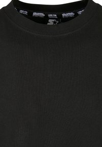 Black crew neck t-shirt with ribbed texture. Made of cotton material, featuring a printed label inside the neckline. Simple, classic design.