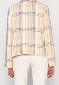 Ruitblazer in lichtgeel, wit en zwart, met een textuurafwerking, notch-kraag en sluiting met één knoop. Korte ontwerp, lange mouwen.