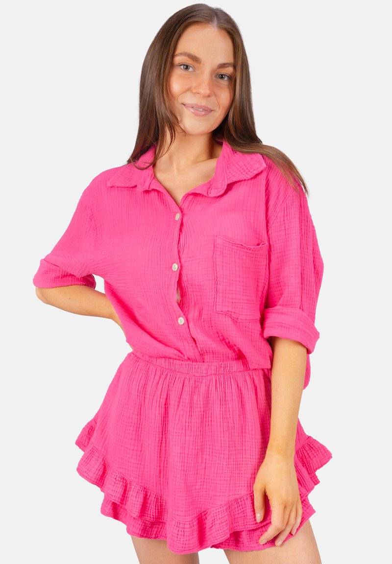 Chemise rose à boutons avec manches retroussées et une poche, associée à une jupe volantée assortie. Fabriquée en tissu texturé.