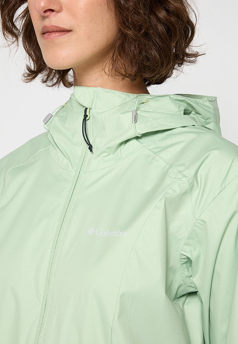 Helle grüne, leichte Jacke mit Kapuze, ausgestattet mit einem Reißverschluss und Logo. Glattes Material mit feiner Textur und verstellbaren Akzenten.