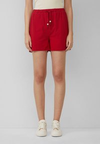 Pantaloni corti in cotone rosso con vita elastica e cordino, caratterizzati da dettagli in legno. Design semplice, lunghezza sopra il cosciotto.