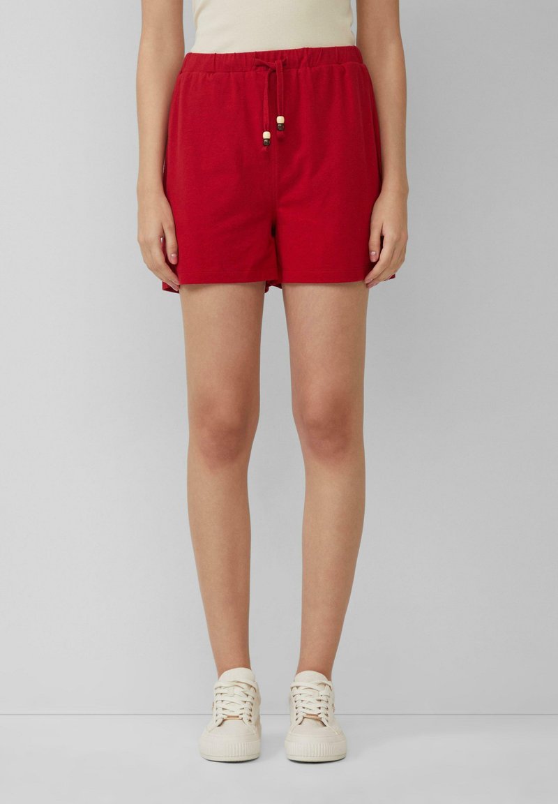 Pantaloni corti in cotone rosso con vita elastica e cordino, caratterizzati da dettagli in legno. Design semplice, lunghezza sopra il cosciotto.