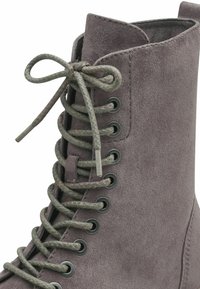 Bottine en suède gris avec un bout rond, un design à lacets, des œillets en métal et une finition texturée. Les lacets sont dans une teinte gris assortie.