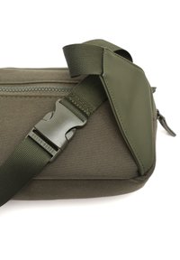 Borsa a tracolla verde oliva con tessuto texturizzato, cintura regolabile e fibbia in plastica. Dotata di un compartimento con cerniera.