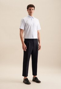 Camicia a maniche corte a righe blu chiaro con colletto classico, abbinata a pantaloni blu scuro e scarpe nere stringate.