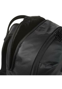 Mochila negra con un tejido suave y duradero, cremalleras dobles y correas de hombro acolchadas. El interior es espacioso y no estructurado.
