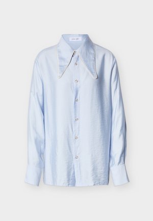 Camicia azzurro chiaro con colletto ampio e appuntito, caratterizzata da piping a contrasto, maniche lunghe e vestibilità leggermente ampia.