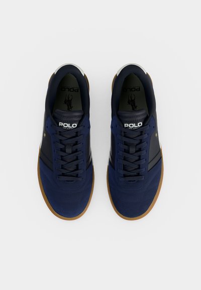 Par de zapatillas Polo Ralph Lauren azul marino con suelas de goma, rayas laterales negras y logo Polo blanco en la lengüeta, atadas y vistas desde arriba.