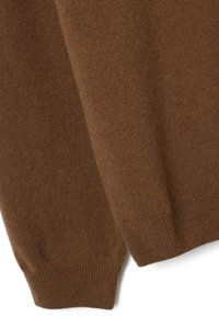 Pull marron tricoté avec une texture douce, présentant des poignets et un ourlet côtelés. Le tissu semble léger et confortable, avec une finition lisse.
