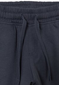Marineblaue Sweatpants mit einem Kordelzugbund, gerippten Bündchen und weichem Stoff. Verfügt über Seitentaschen und minimale Nähdetails.