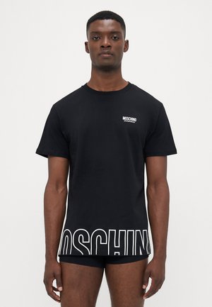 Schwarzes Baumwoll-T-Shirt mit rundem Ausschnitt und kurzen Ärmeln. Auffälliges weißes "MOSCHINO"-Logo am unteren Rand. Einfaches Design, weicher Stoff.