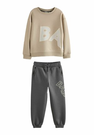 Beige sweatshirt with large "BA" letters paired with dark gray sweatpants featuring "BAKER" text on the left leg, elastic cuffs and waistband.