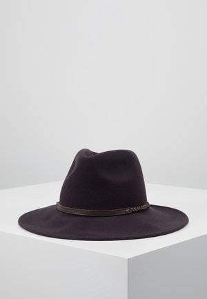 Chapeau fedora noir à large bord avec un bandeau en cuir tressé marron, présenté sur un socle blanc sur un fond uni.