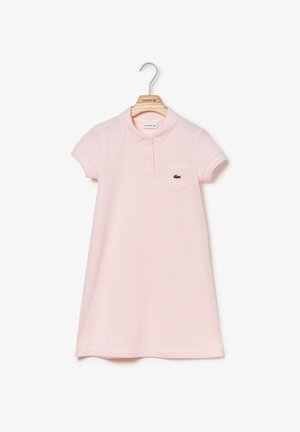 Lyserød poloshirt-kjole med korte ærmer, krave, for- knapper, lille lomme og grønt krokodille-logo på en træbøjle.
