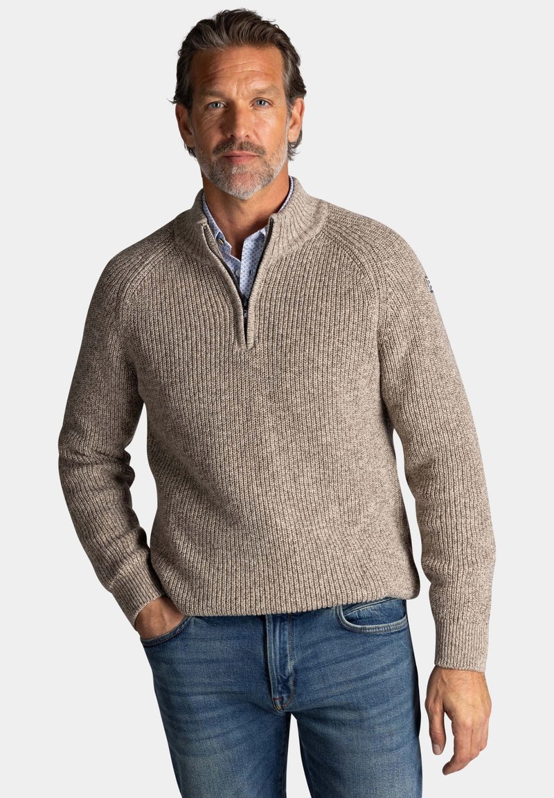 Beige gebreide trui met een halve rits en een neklap, met geribbelde textuur, gecombineerd met klassieke blauwe jeans in een casual pasvorm.